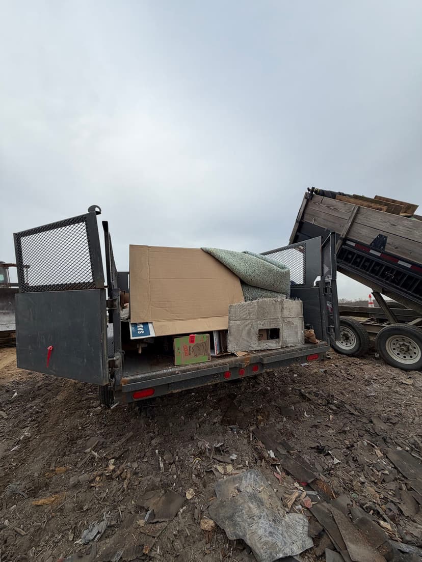 Dump truck filled with construction debris and cardboard at a recycling site.